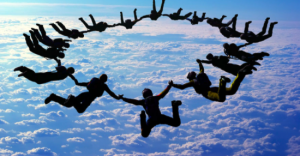 A picture of a circle of parachutists linking arms and falling through clouds